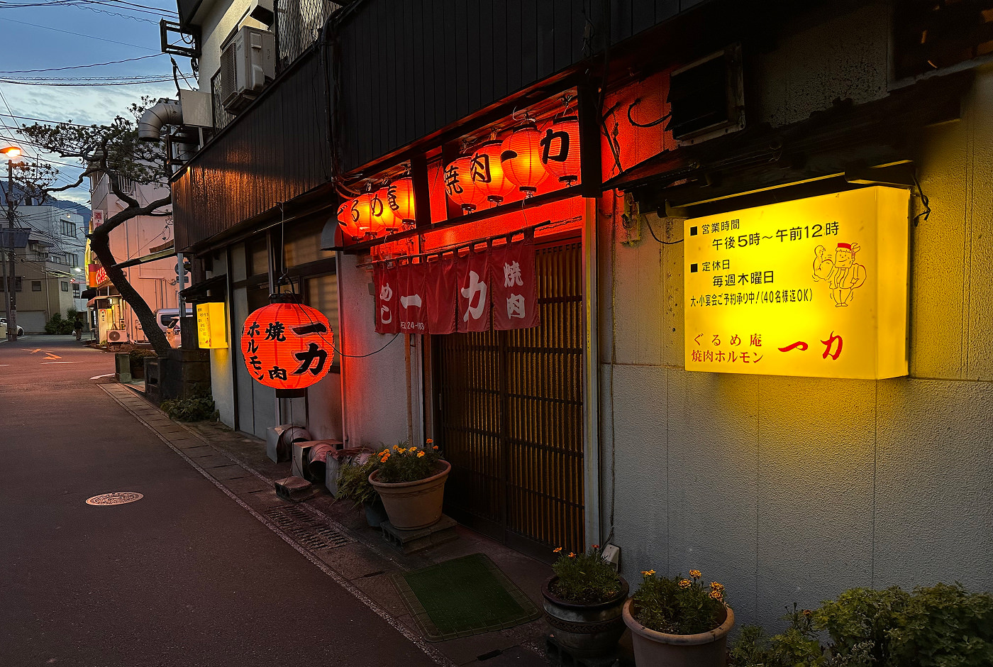 Fasad till restaurang med skjutdörr av trä och röda runda lyktor med svart japansk skrift på.