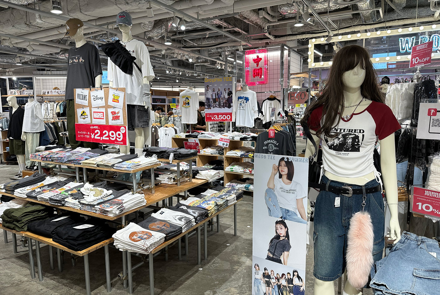 Stor butikslokal med några neonskyltar och många hyllor och skyltdockor med t-shirts med tryck på.