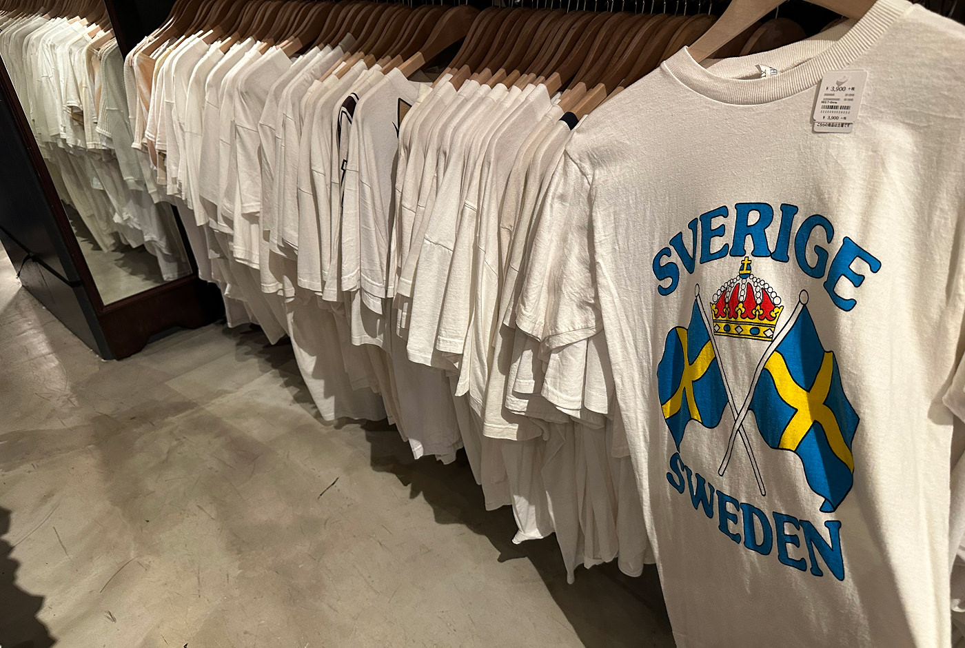 En lång rad med hängande vita t.shirts. Den närmast kameran har texten "Sverige Sweden".