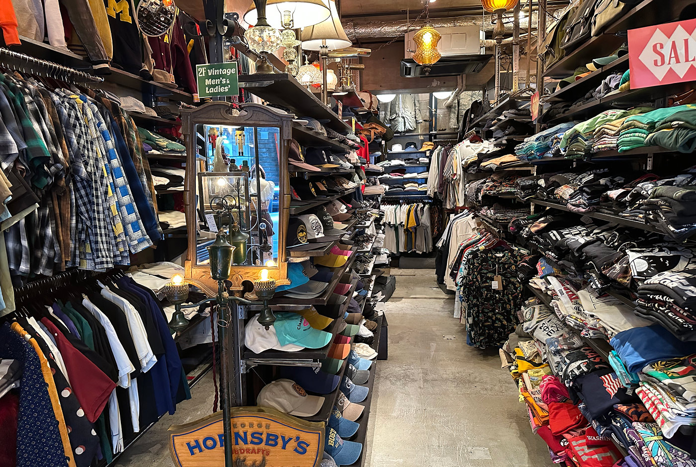 En proppfyll klädbutik med flera hyllor med skjortor, t-shirts och kepsar.