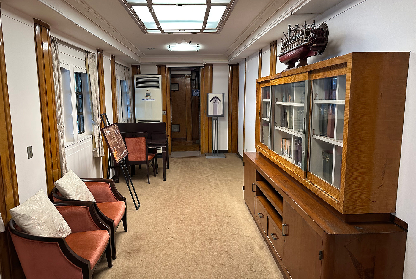 Rum i ett passagerarfartyg möblerat med några fåtöljer och en bokhylla.