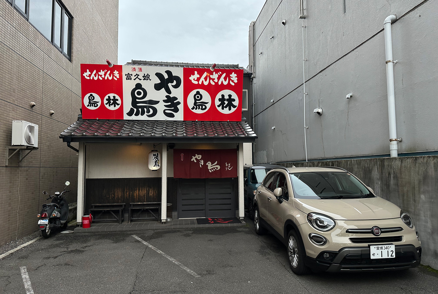 Liten restaurang i en gränd. En bil och en moped är parkerade utanför.