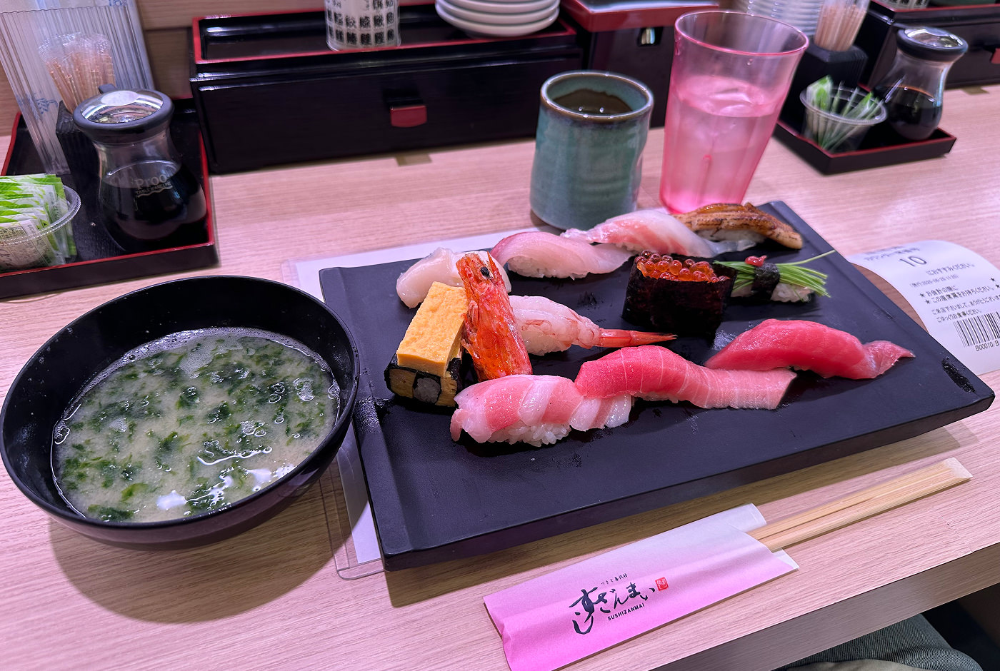 En skål med misosoppa och en svart bricka med elva bitar sushi.