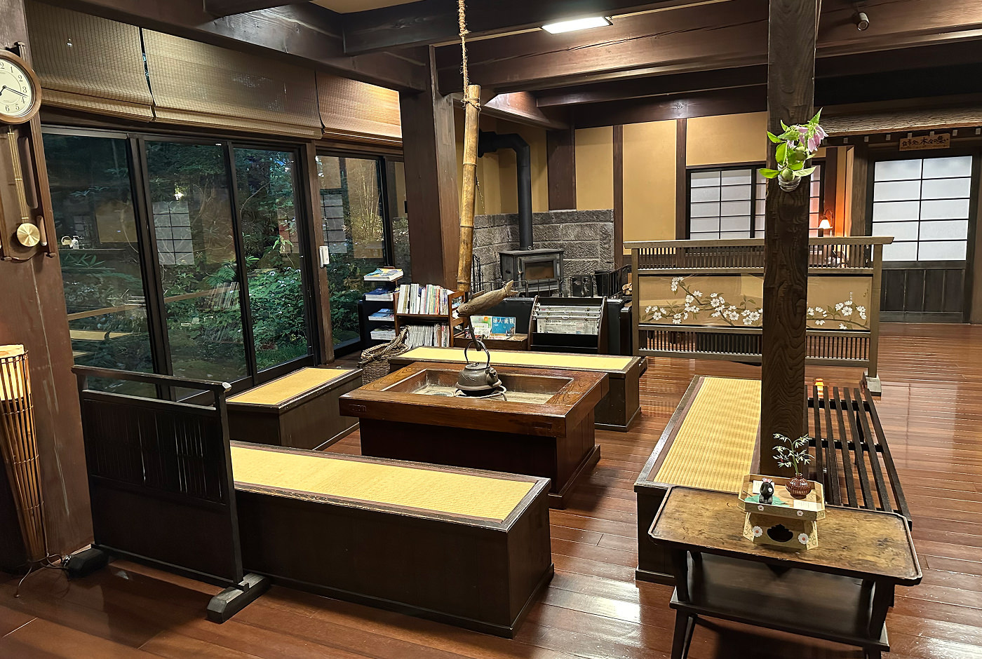 Lobby i ett traditionellt ryokan. Golvet är brunt och väggarna ljusgula. Det står flera bänkar på golvet och en öppen spis syns i fjärran.