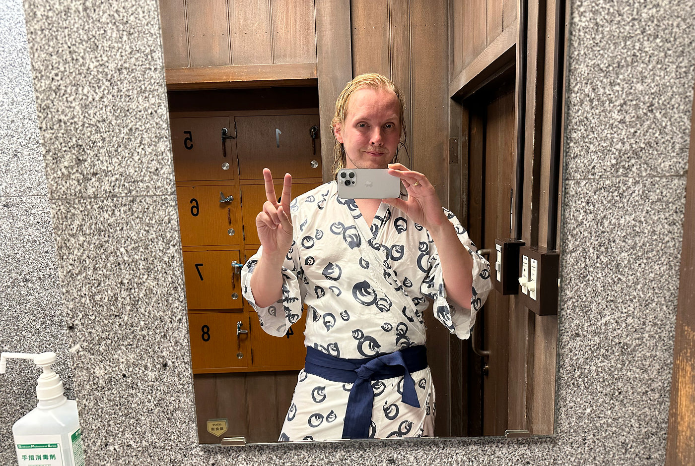 Jag står i en ljus yukata med mörkt bälte och visar fredstecknet framför en spegel.