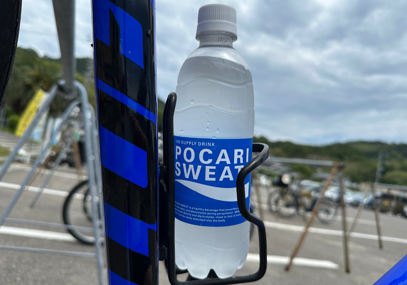 En flaska med ljus sportdryck och texten "Pocari Sweat" i en hållare på en cykel.