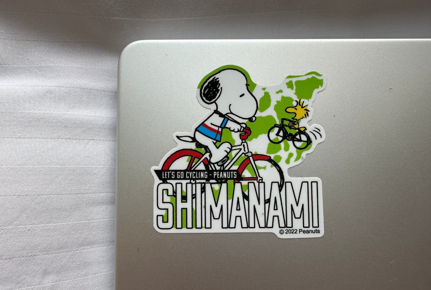 Klistermärke där Snobben och Woodstock cyklar. Text lyder "Shimanami".