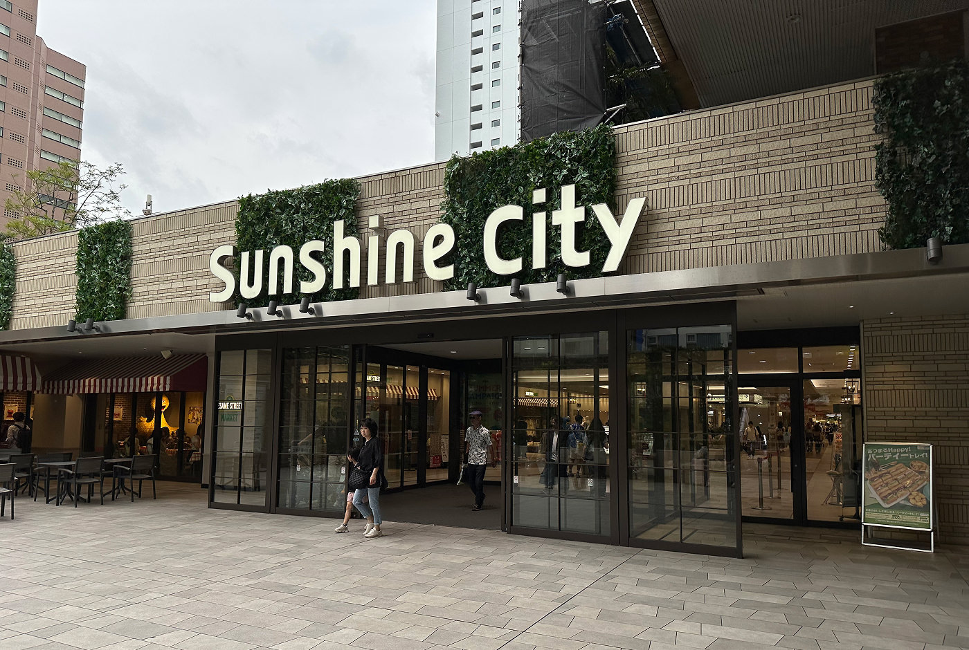 Ingång till köpcentret Sunshine City. En del av fasaden består av glasdörrar, resten av ljust murbruk.