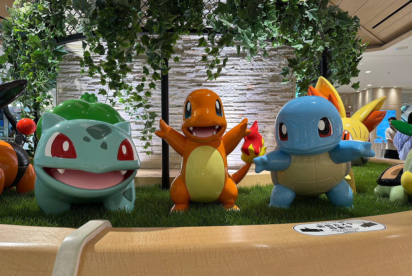 Statyer tre pokémons står bredvid varandra i olika poser. Det är Bulbasaur, Charmander och Squirtle.