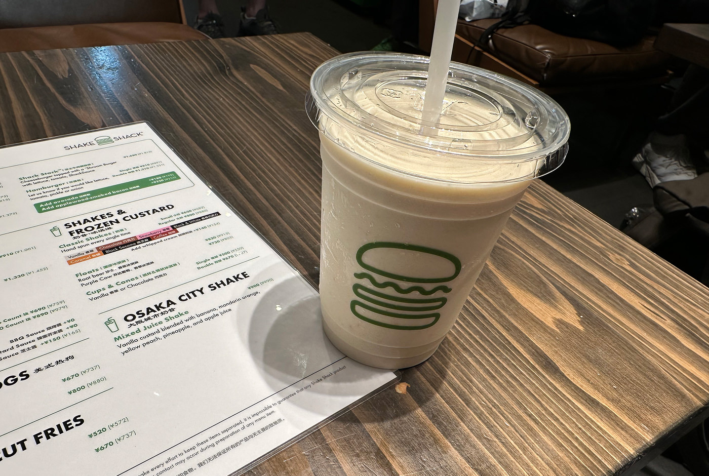 Milk shake i en genomskinlig platskopp med sugrör- Till vänster ser men en vit meny där en sektion med text lyder "Osaka City Shake".