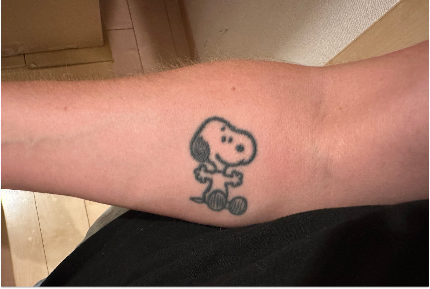 Underarm med en tatuering med Snobben på. Snobben gör en gest i form av en kram.