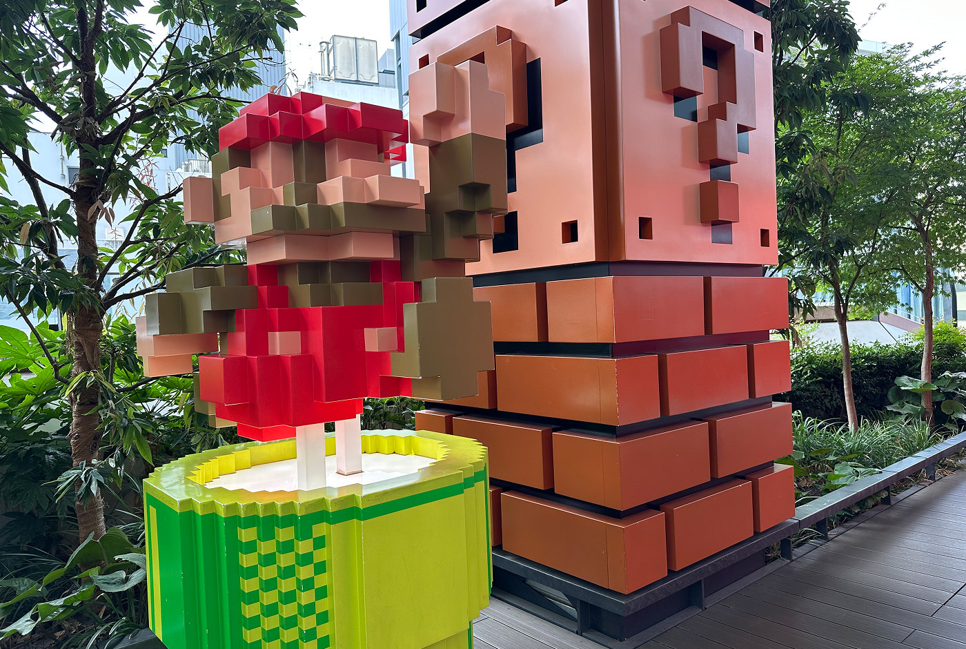 En installation av Super Mario som hoppar ur ett grönt rör framför några bruna tegelblock. Han är designad som sin pixliga version från 80-talet.