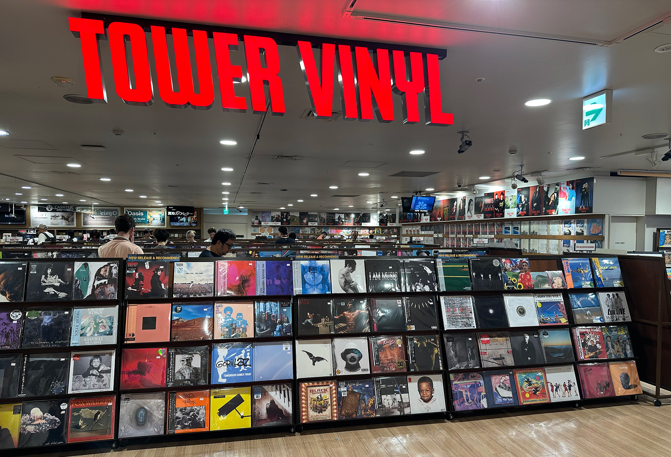 Stor våning i en skivbutik med många hyllor fyllda med vinyler. En röd skylt ovan lyder "Tower Vinyl".