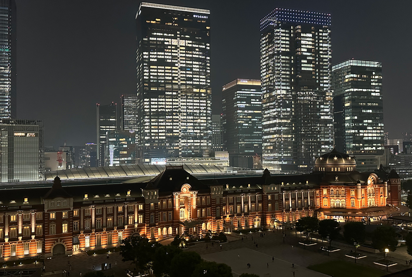 Utsikt från ovan över Tokyo Station med sin fint upplysta röda tegelfasad. Bakom finns flera upplysta skyskrapor.
