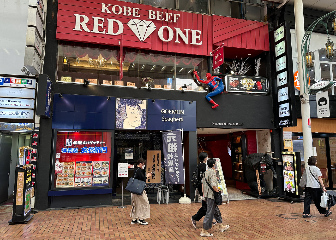 Ingången till en restaurang på en gågata. Högt upp är en röd skylt med den vita texten "Kobe Beef Red One".