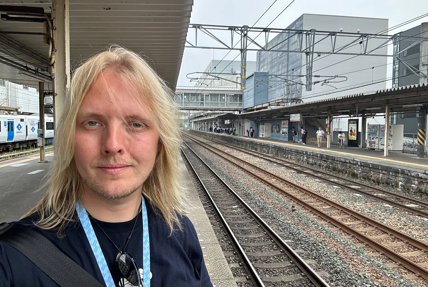Jag står på en tågperrong och tittar in i kameran och ler subtilt.