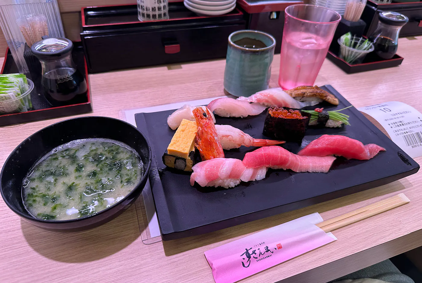 En skål med misosoppa och en svart bricka med elva bitar sushi.