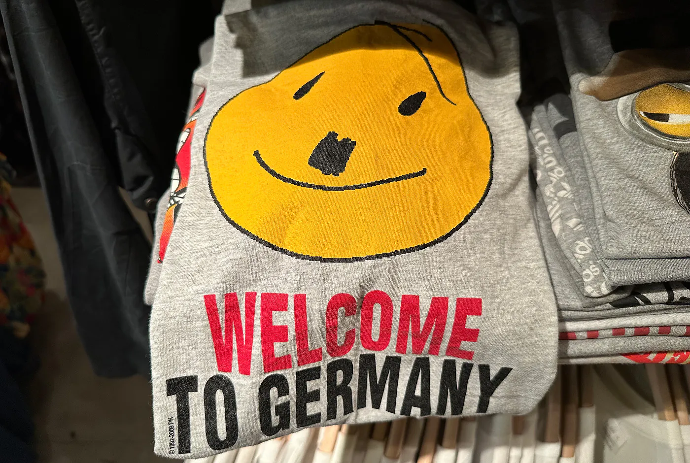 En grå tröja med texten "Welcome to germany" och ett smiley-ansikte som ser ut som Adolf Hitler.