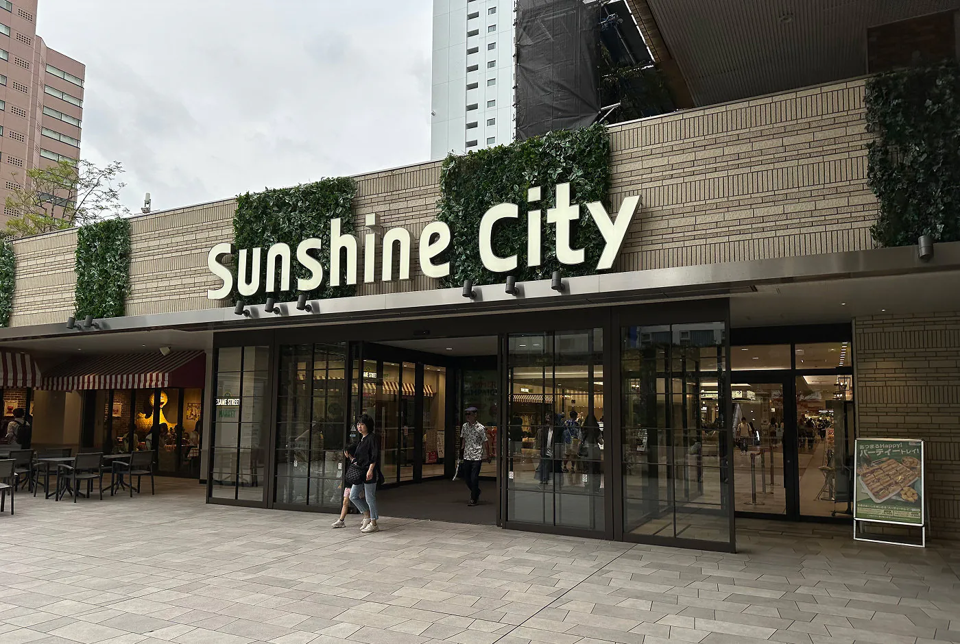 Ingång till köpcentret Sunshine City. En del av fasaden består av glasdörrar, resten av ljust murbruk.