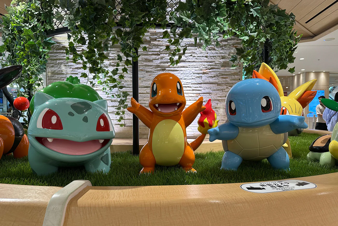 Statyer tre pokémons står bredvid varandra i olika poser. Det är Bulbasaur, Charmander och Squirtle.
