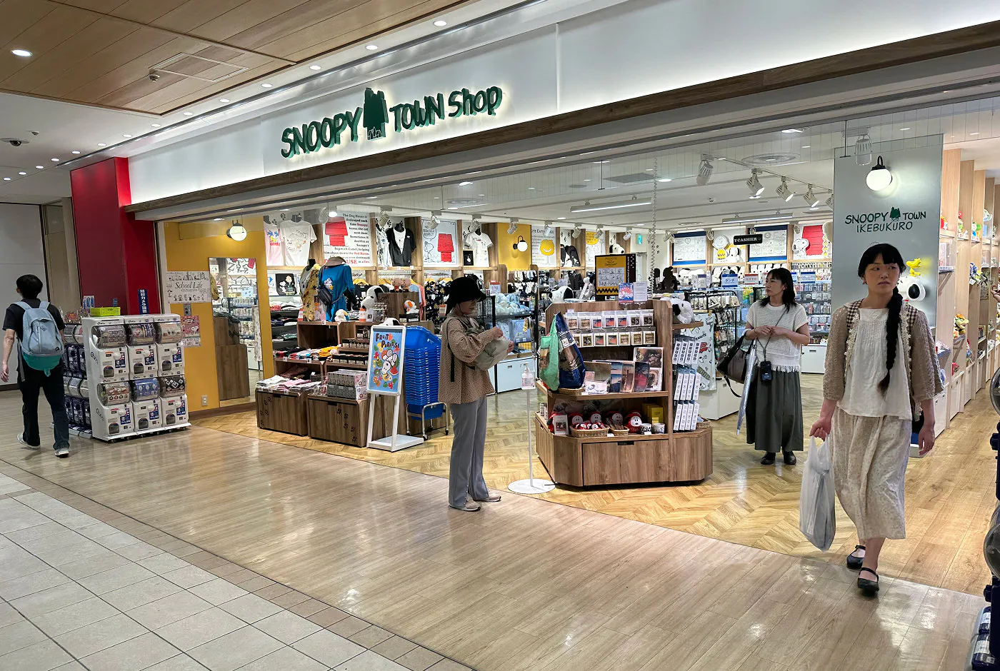 En ljus butik med många hyllor med kläder, kramdjur, kort, porslin med mera. Skylten ovan lyder "Snoopy Town Shop".