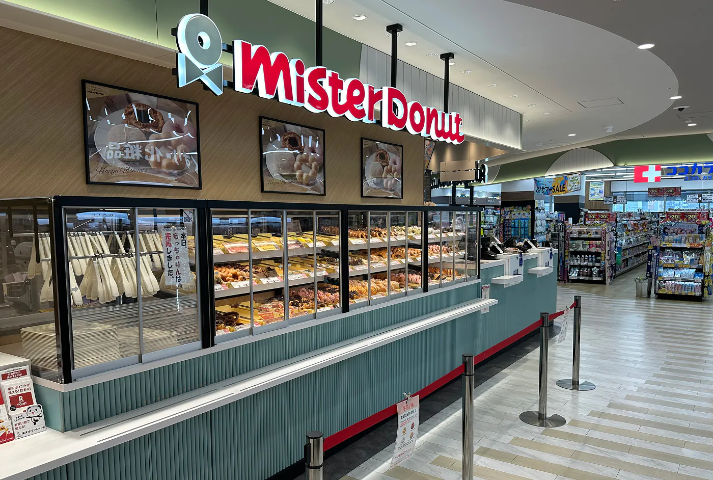 Kafé med flera glasskåp fyllda med snyggt garnerade munkar. En skylt ovan lyder "Mister Donut".
