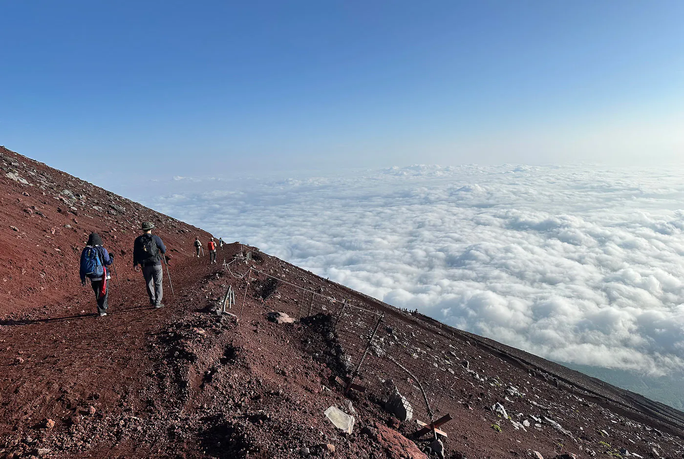 En lång backe som går i sicksack nedför ett enormt berg bestående av röd vulkansten. I fjärran syns ett molntäcke så långt ögat kan nå.
