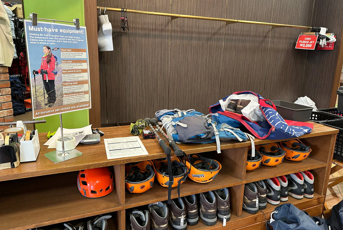 En trädisk i en butik. ovanpå disken ligger ett par gångstavar, en ryggsäck och en påse med ett par kängor i.