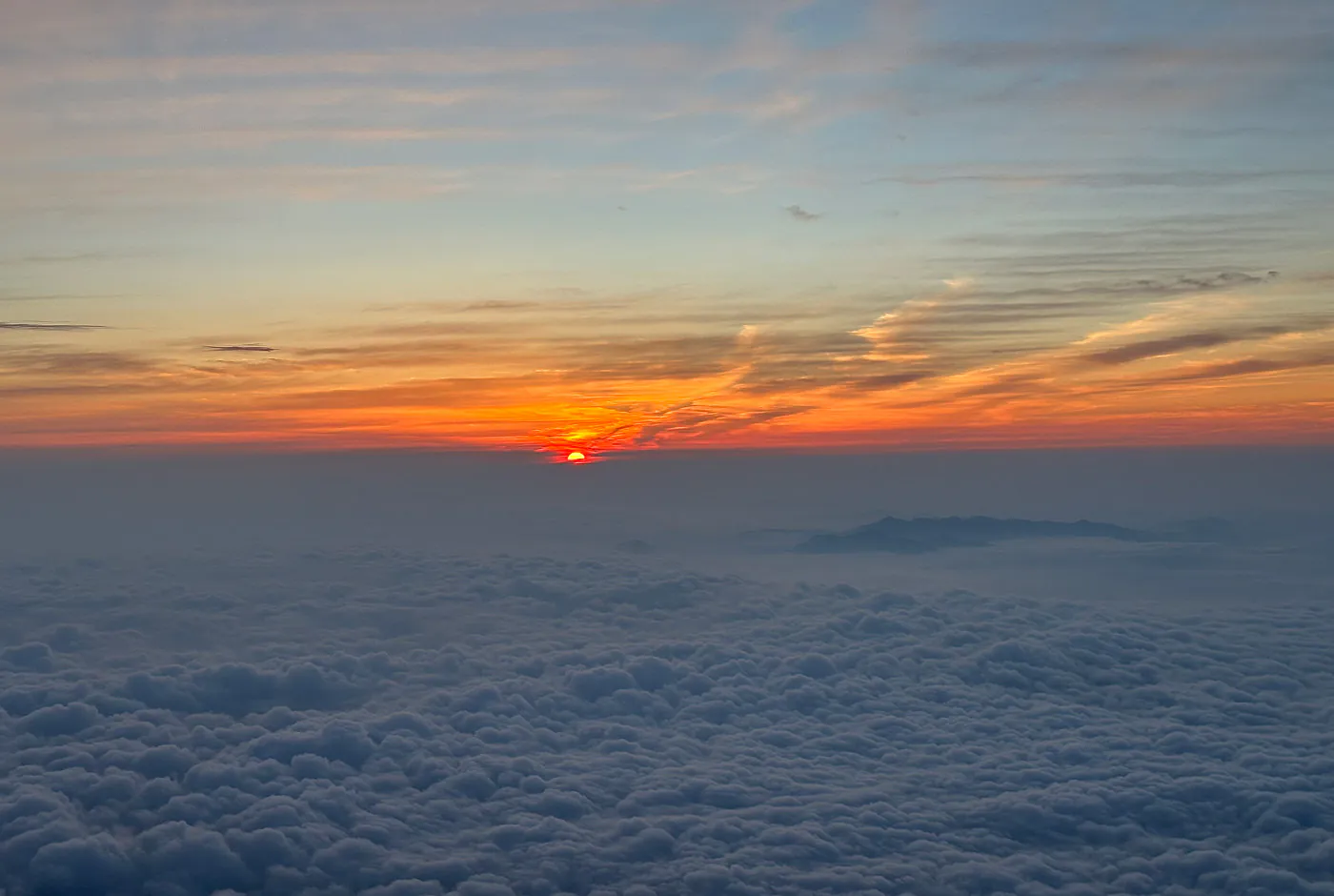 Rödgul soluppgång ovanför ljusblåa moln.