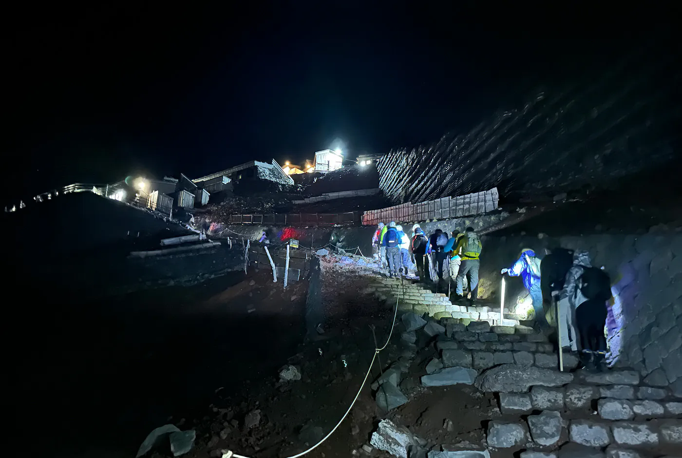 Trappa upp för en snäv och ganska brant vandringsled. Det är natt och olika lampor lyser upp leden.