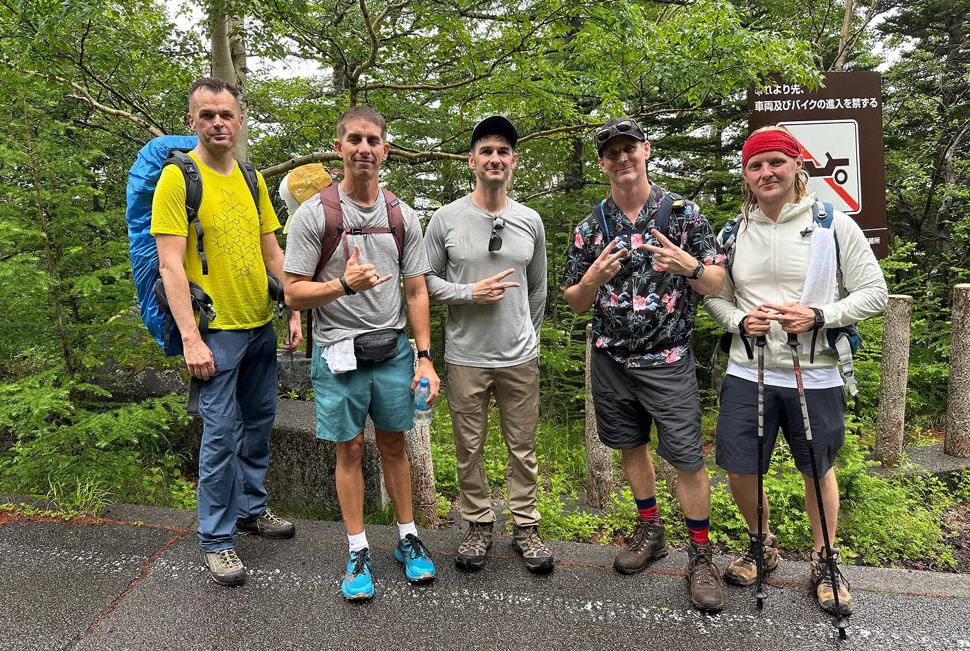 Fem män i vandringskläder står långs med en väg och poserar. Jag står längst till höger och håller i två gångstavar.