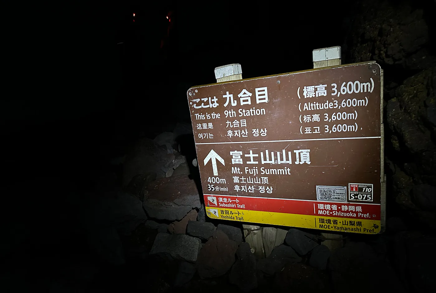 En skylt omgivet av mörker som säger att det är 400 meter till toppen av Mount Fuji och att det kommer ta 35 minuter att gå.