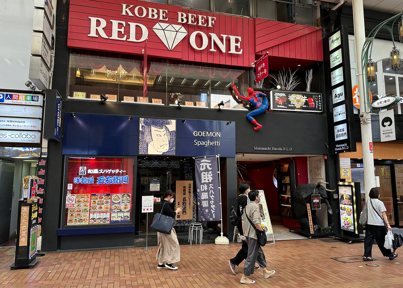 Ingången till en restaurang på en gågata. Högt upp är en röd skylt med den vita texten "Kobe Beef Red One".